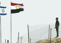 EGYPTIAN AND ISRAELI flags flutter next to each other at the Taba border crossing.