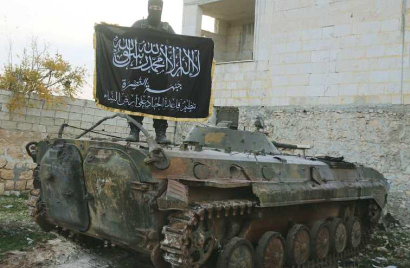 A member of al-Qaida’s Nusra Front fighting with other Sunni Islamists in support of the Syrian opposition pose on a tank near Aleppo in November 2014. (photo credit: REUTERS)