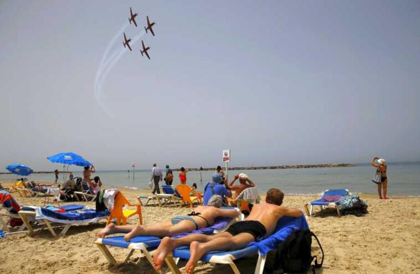Beachgoers watch the Israeli Air Force Aerobatic team rehearse over the Mediterranean Sea in preparation for an aerial display on Israel's Independence Day in Tel Aviv April 20, 2015. (photo credit: REUTERS)