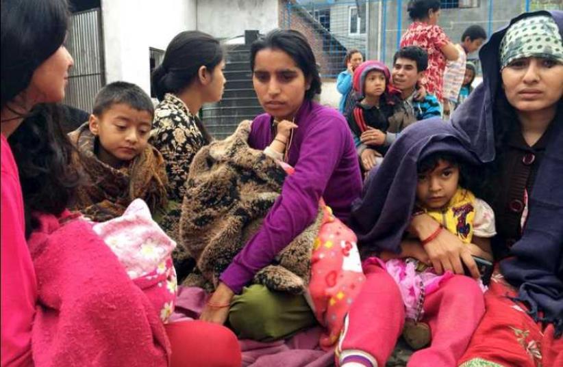 People wait at a school after a 7.7 magnitude earthquake struck, in Kathmandu, Nepal, April 25, 2015. (photo credit: REUTERS)