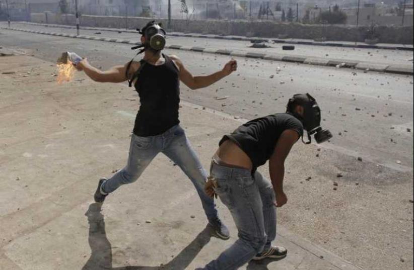 A Palestinian protester hurls a Molotov cocktail at Israeli troops following a demonstration against the Israeli offensive in Gaza, in the West Bank town of Bethlehem. (photo credit: REUTERS)