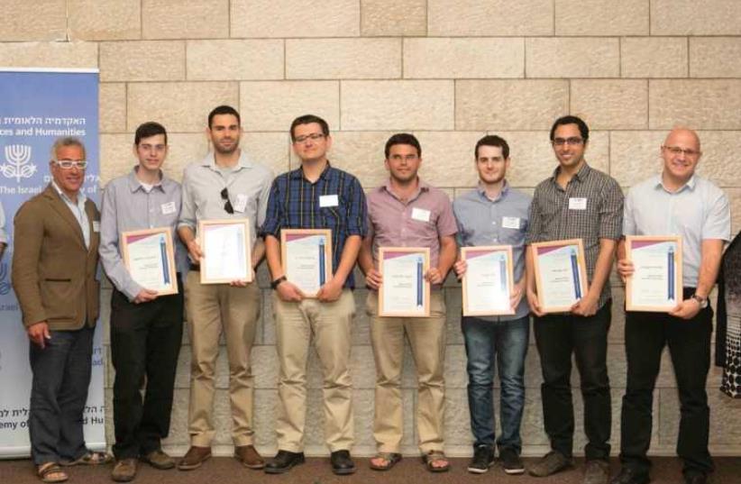 ADAMS FELLOWSHIP winners pose with their accolades, alongside Marcel Adam’s children, Linda and Silvan. (photo credit: Courtesy)