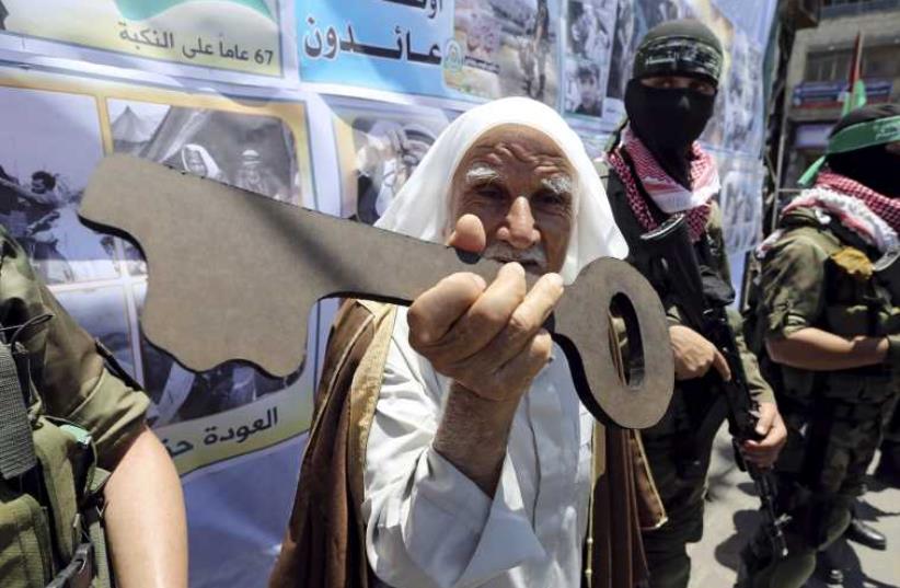 A Palestinian man holds a symbolic key next to Hamas militants during a rally after Nakba Day in Rafah (photo credit: REUTERS)