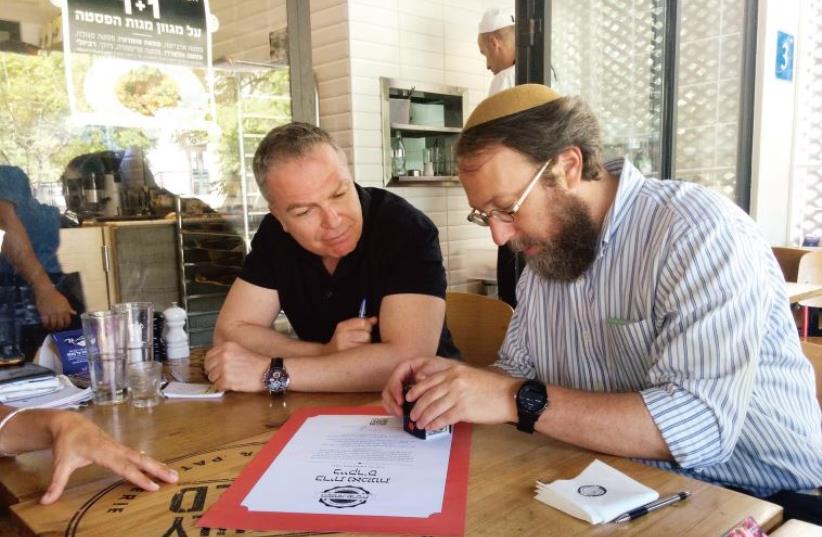 Rabbi Aaron Leibowitz and Baker’s Boulangerie and Patisserie owner Lior Glickman sign the ‘trust alliance’ certification. (photo credit: Courtesy)