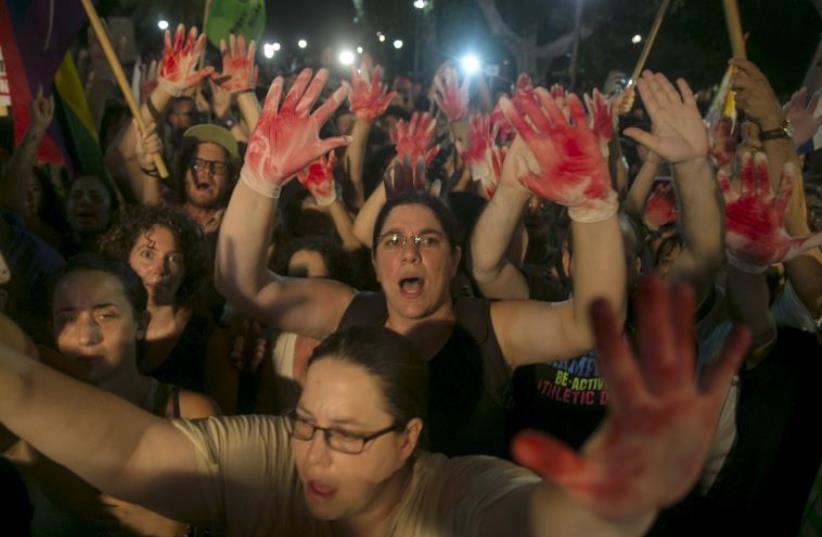 Protesters hold up gloves covered in red during a protest against the violence towards the gay community in Tel Aviv August 1, 2015 (photo credit: REUTERS)