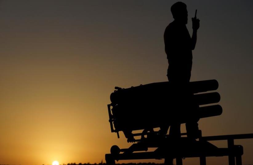 A Free Syrian Army fighter talks on a walkie-talkie near a rocket launcher in Daraa (photo credit: REUTERS)