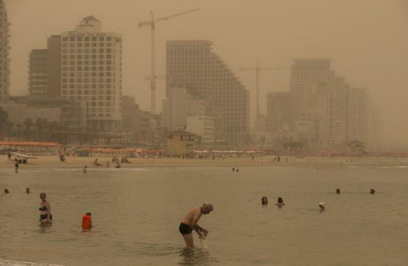 Beachgoers bath at the Mediterranean Sea during a sandstorm in Tel Aviv (photo credit: REUTERS)