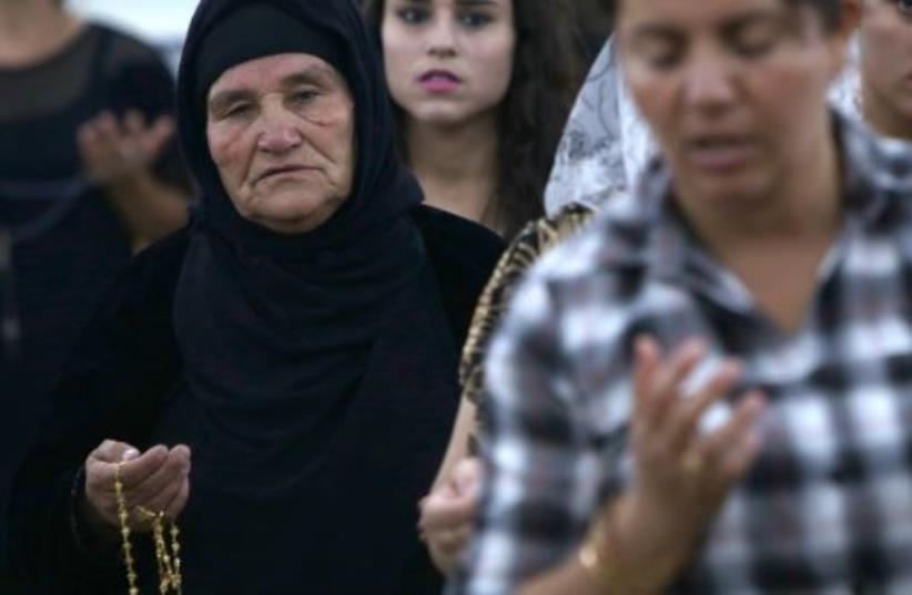 Iraqi Christians who fled the violence in the northern city of Mosul, pray at the MarAfram church in the village of Qaraqush, about 30 kms east of Mosul (photo credit: SAFIN HAMED / AFP)