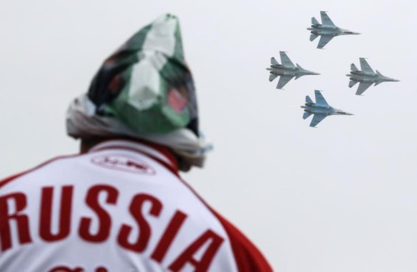 A spectator watches Sukhoi Su-30SM jet fighters of the Sokoly Rossii (Falcons of Russia) aerobatic team perform during the MAKS International Aviation and Space Salon in Zhukovsky, outside Moscow (photo credit: REUTERS)