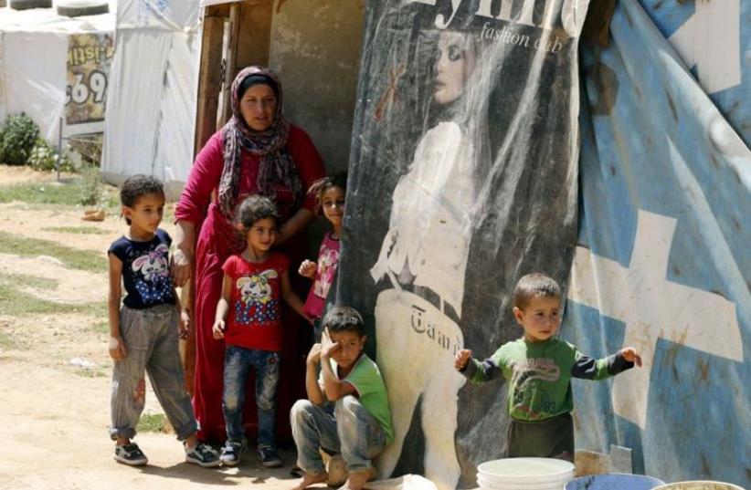 Syrian refugees shelter in a makeshift tent in the Bekaa Valley, part of the 1.15 million refugees being hosted by Lebanon (photo credit: MOHAMED AZAKIR / REUTERS)