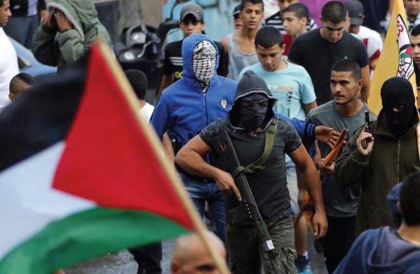 Palestinian gunmen in Shuafat carry weapons during a funeral march for a Palestinian terrorist, shot dead by police after stabbing two Israelis in Jerusalem’s Old City (photo credit: AMMAR AWAD / REUTERS)
