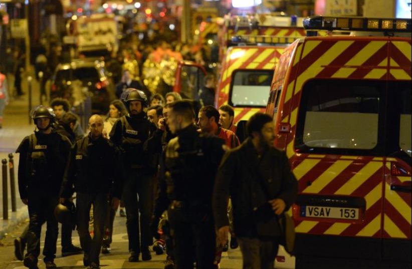 Police forces and rescuers walk through rue Oberkampf near the Bataclan concert hall in central Paris, early on November 14, 2015 (photo credit: AFP PHOTO/MIGUEL MEDINA)