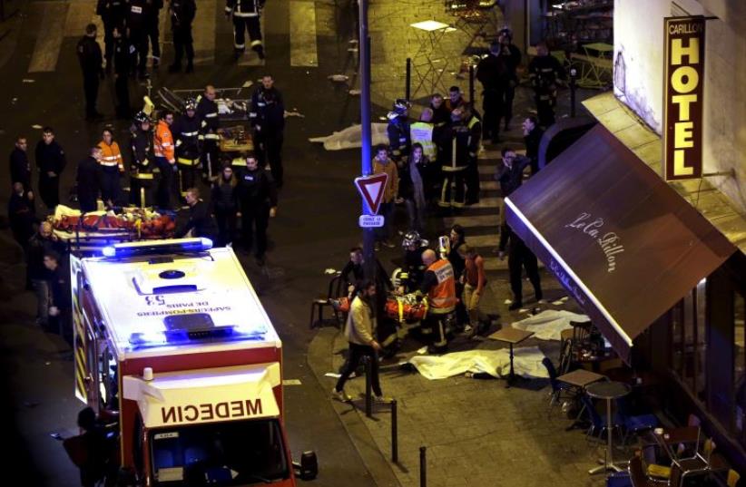 Rescue service personnel working outside a restaurant following shooting incidents in Paris, France, November 13, 2015 (photo credit: REUTERS)