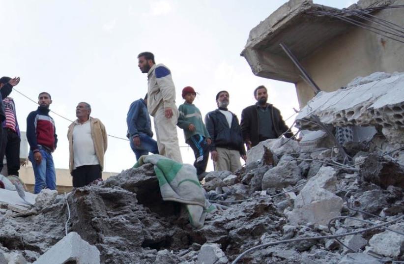 Residents of Nawa city in Syria inspect the damage after a reported strike against ISIS positions by the Russian Air Force, November 21 (photo credit: REUTERS)