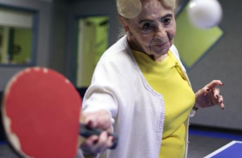 Holocaust survivor Betty Stein, 92, (L) and Eli Boyer, 91, play ping pong at a program for people with Alzheimer's and dementia at the Arthur Gilbert table tennis center in Los Angeles (photo credit: REUTERS)