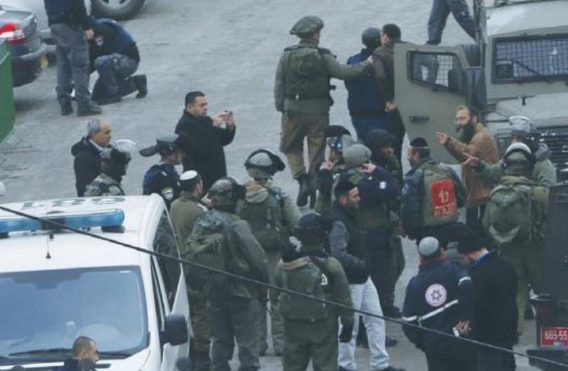 SECURITY PERSONNEL inspect the scene where a female soldier was shot yesterday in Hebron. (photo credit: REUTERS)