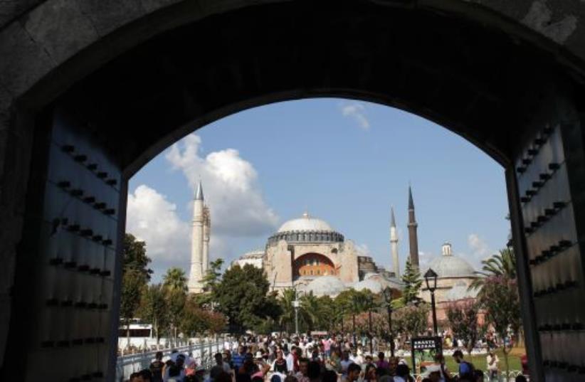 Local and foreign visitors, with the Byzantine-era monument of Hagia Sophia in the background, stroll at Sultanahmet square in Istanbul (photo credit: REUTERS)