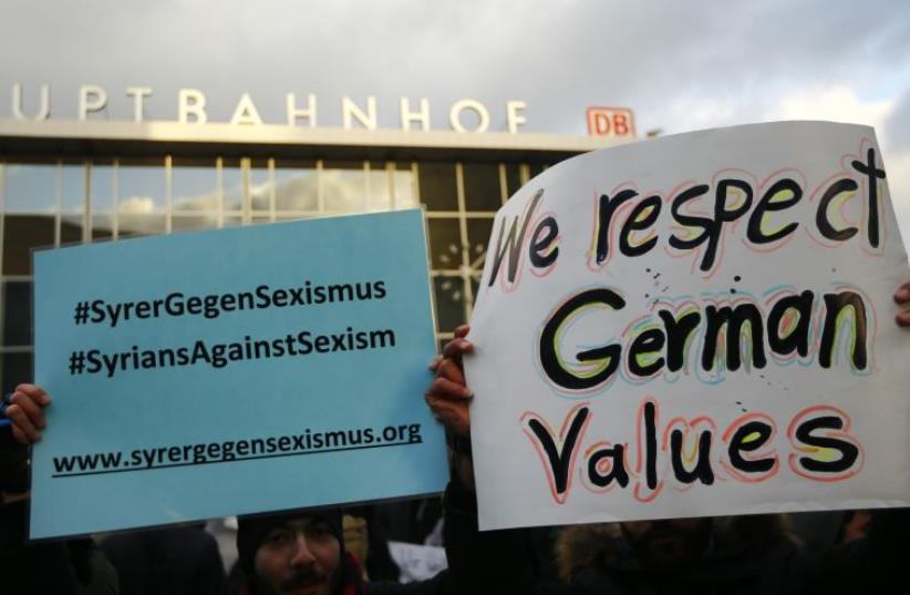 People from Syria hold placards reading 'Syrians against sexism' during a rally outside the main railway station in Cologne, Germany, January 16, 2016, where the vast majority of dozens of New Year Eve assaults on women took place.  (photo credit: REUTERS)