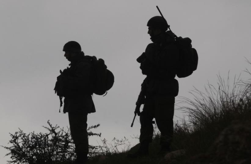 IDF soldiers stand guard during a demonstration by Palestinians against the closure of the main road in Jabaa area south of the West Bank city of Bethlehem (photo credit: REUTERS)