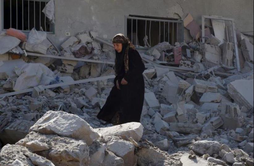 A woman makes her way through the rubble of damaged buildings after airstrikes by pro-Syrian government forces in the rebel held town of Dael, in Deraa Governorate, Syria February 12, 2016. (photo credit: REUTERS)