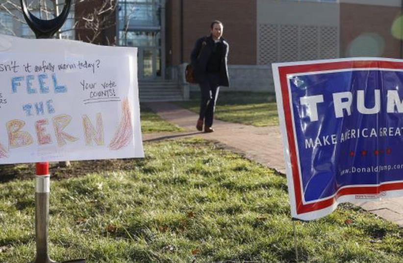 A Virginia voter is framed by a sign in support of Bernie Sanders (L) and a Donald Trump campaign sign (R) after casting his ballot in Arlington, Virginia. (photo credit: REUTERS/GARY CAMERON)