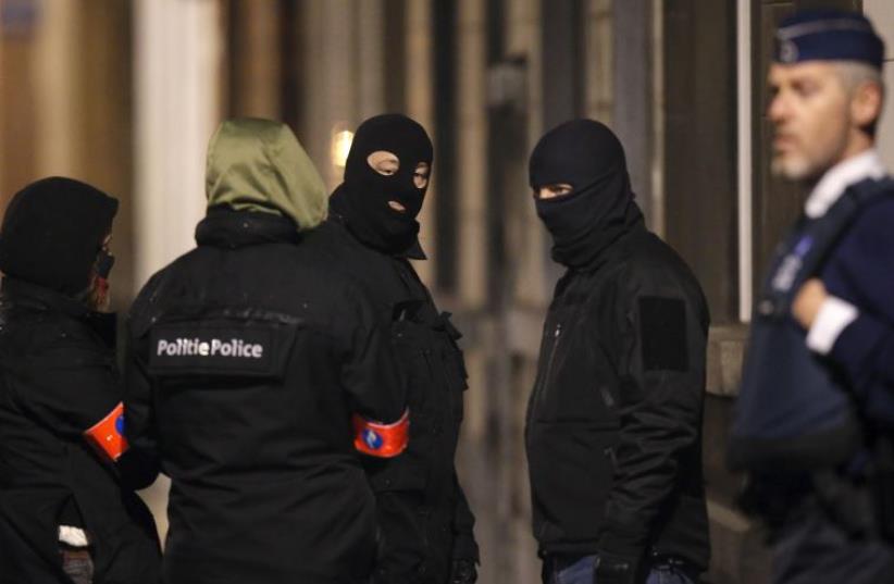 Masked Belgian police secure the entrance to a building in Schaerbeek during police operations following Tuesday's bomb attacks in Brussels, Belgium, March 25, 2016 (photo credit: REUTERS)