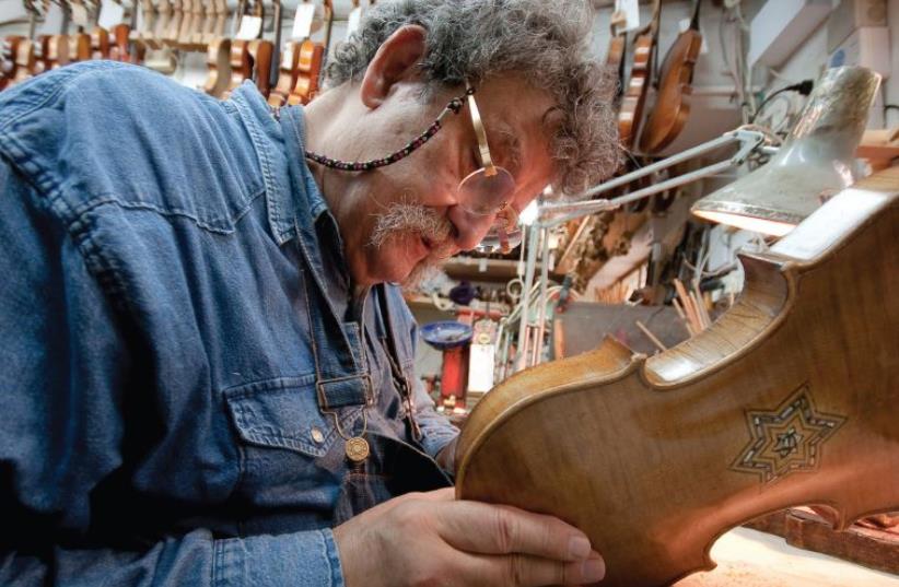 Second-generation violion builder Amnon Weinstein inspects an instrument (photo credit: ZIV SHENHAV)