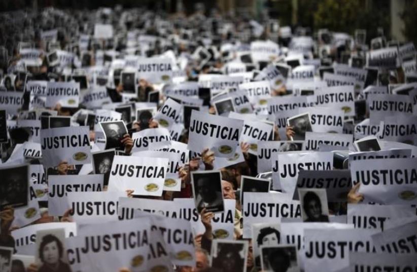 DATE IMPORTED: July 18, 2013 Thousands of people hold up signs reading, "Justice" as they gather to commemorate the 19th anniversary of the 1994 bombing of the Argentine Israeli Mutual Association (AMIA) Jewish community center in Buenos Aires July 18, 2013. (photo credit: REUTERS/MARCOS BRINDICCI)