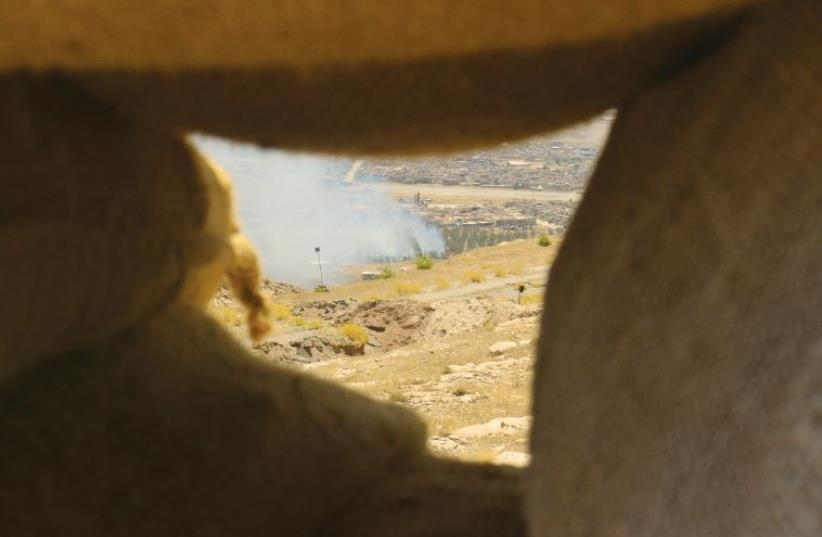 An explotion is seen on territory controlled by Islamic State, fired by Kurdish Peshmerga fighters in Bashiq (photo credit: LAURA KELLY)