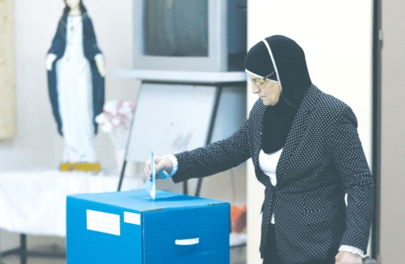 AN ISRAELI ARAB casts her vote at a polling station inside a church in the northern village of Reina on March 17, 2015. (photo credit: REUTERS)