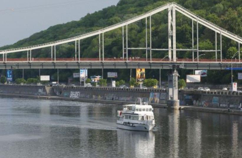 A MOTORBOAT passes under a footbridge over the Dnieper River in Kiev, Ukraine. (photo credit: REUTERS)