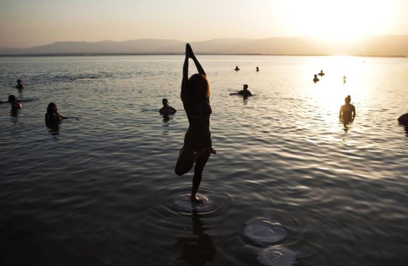 A woman practices yoga during a mass floating event in the Dead Sea (photo credit: REUTERS)