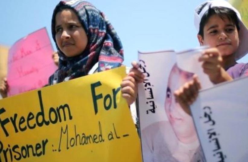 Palestinian demonstrators take part in a protest in solidarity with Mohammad El Halabi, World Vision's manager of operations in Gaza who was accused by Israel of funnelling millions of dollars in aid money to Hamas, organised by foundations and societies benefiting from World Vision in Gaza City Aug (photo credit: REUTERS)