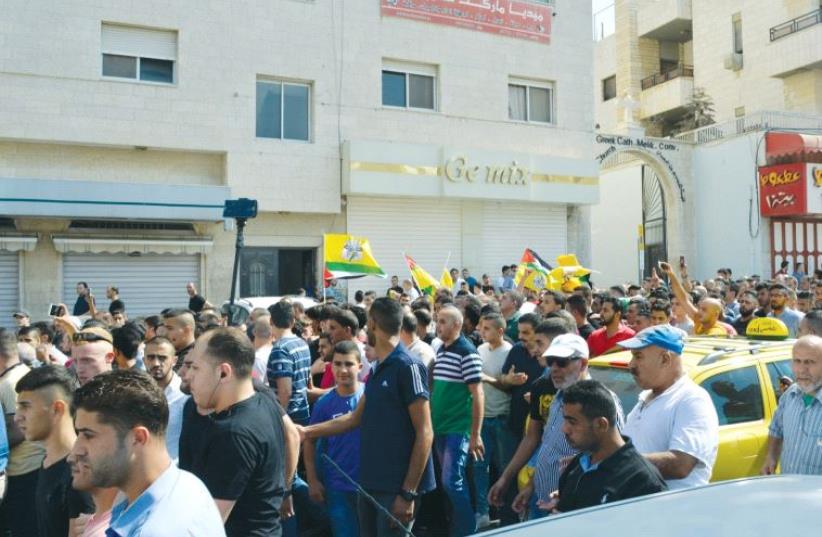 Protesters wave Fatah and Palestinian flags during a demonstration in Nablus in August 2016. (photo credit: UDI SHAHAM)