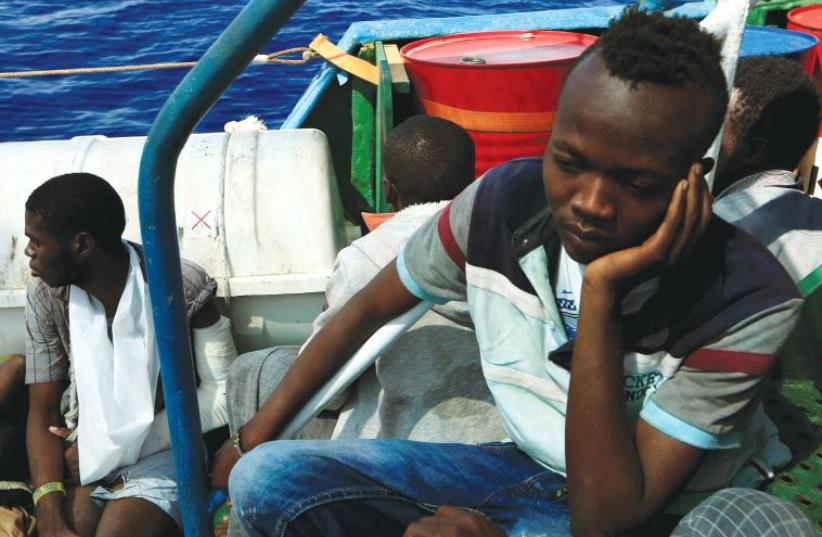 ISSAM IBRAHEEM (right), 13, a migrant from Darfur, sits inside a vessel after he was rescued from an overcrowded dinghy by members of the German NGO Jugend Rettet. The rescue operation took place off the Libyan coast in the Mediterranean Sea last week. (photo credit: REUTERS)