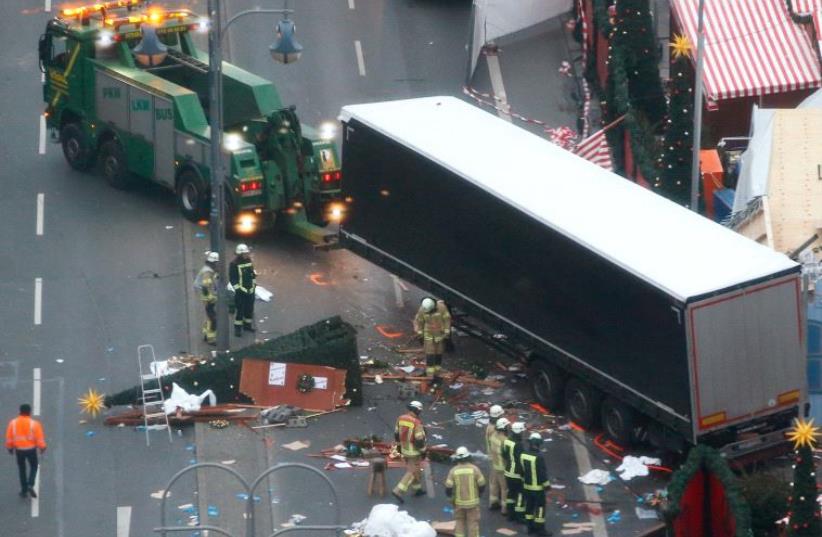 Rescue workers tow the truck which ploughed into a crowded Christmas market in the German capital last night in Berlin, Germany, December 20, 2016 (photo credit: REUBEN BRAND)