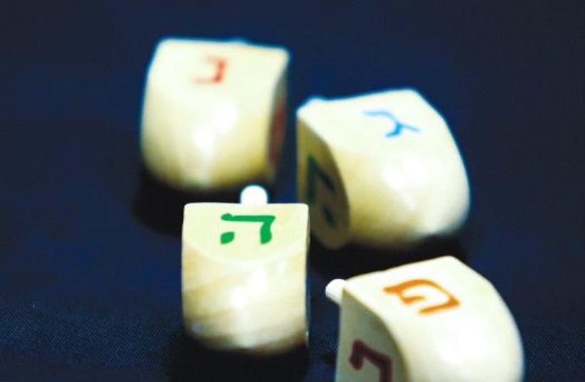 HANUKKA DREIDELS display the letters of the Hebrew acronym for ‘A great miracle happened here.’ (photo credit: MARC ISRAEL SELLEM/THE JERUSALEM POST)