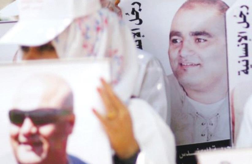 PALESTINIANS HOLD POSTERS of Mohammad El Halabi, World Vision’s manager of operations in the Gaza Strip, at a protest to show support for him in Gaza City on August 7. (photo credit: REUTERS)