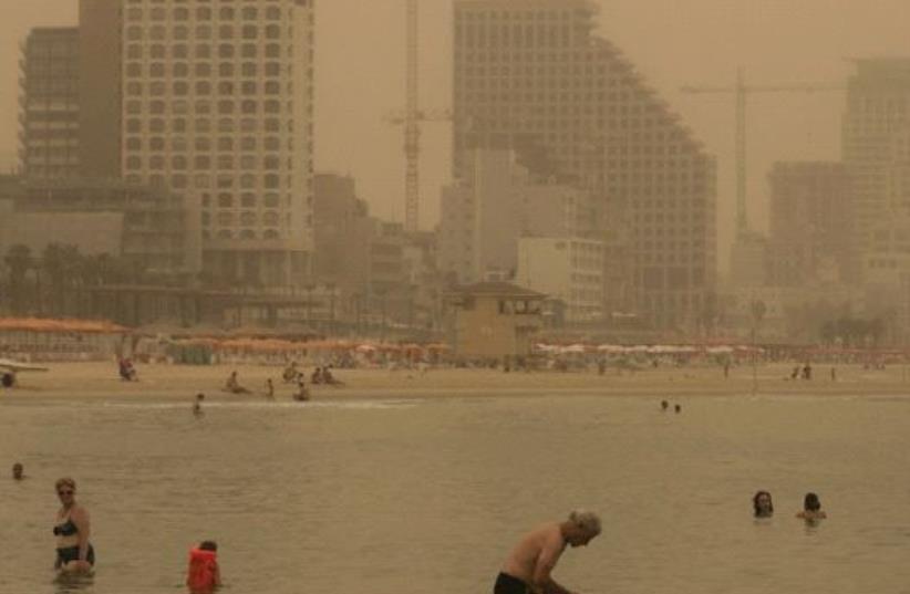 BEACHGOERS in Tel Aviv ignore the August 2015 sand and dust storm to take a swim. ( (photo credit: REUTERS)