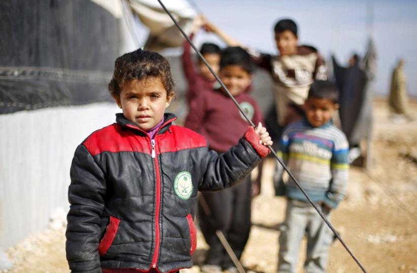 Syrian refugee children pose as they play near their families' residence at Al Zaatari refugee camp in the Jordanian city of Mafraq, near the border with Syria, January 30, 2016. (photo credit: REUTERS)