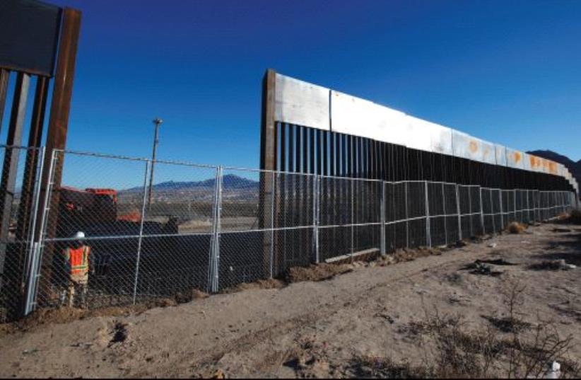 A WORKER STANDS next to a newly built section of the US border fence at Sunland Park, New Mexico, opposite the Mexican border city of Ciudad Juarez, on Wednesday. Picture taken from the Mexico side of the border. (photo credit: JOSE LUIS GONZALEZ/REUTERS)