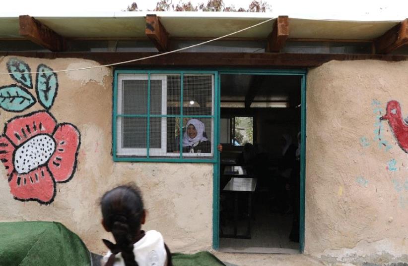 A BEDUIN SCHOOLGIRL looks out the window of her classroom at the Al-Khan al-Ahmar school, near the West Bank city of Jericho. (photo credit: REUTERS)