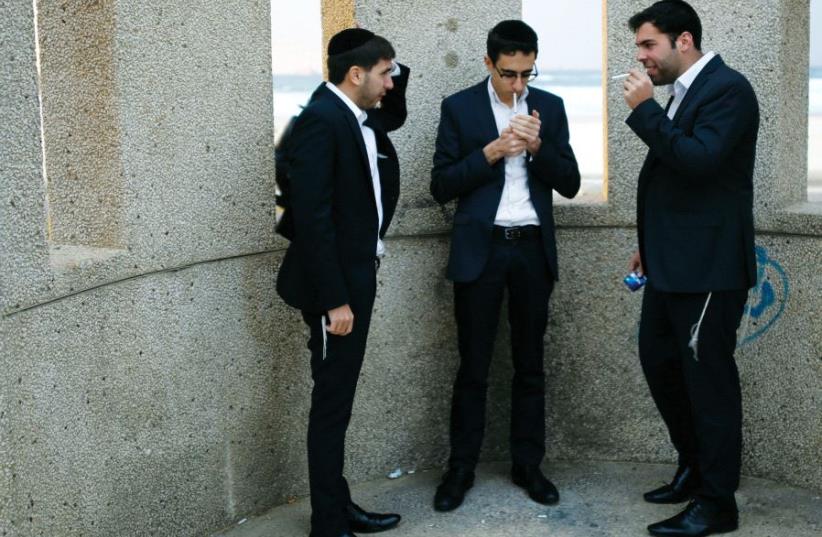 Utra-orthodox men smoke cigarettes near the beach in Ashdod (photo credit: REUTERS)