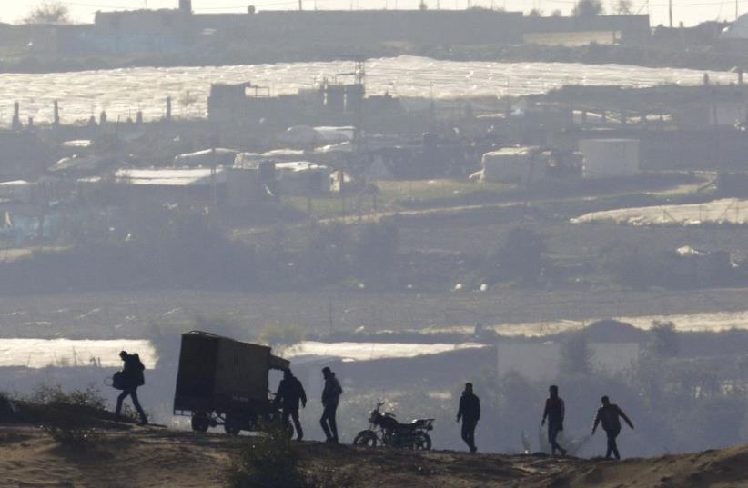 PALESTINIANS WALK near the Israel-Gaza border inside Gaza, where Hamas still holds Israeli citizens. (photo credit: REUTERS)