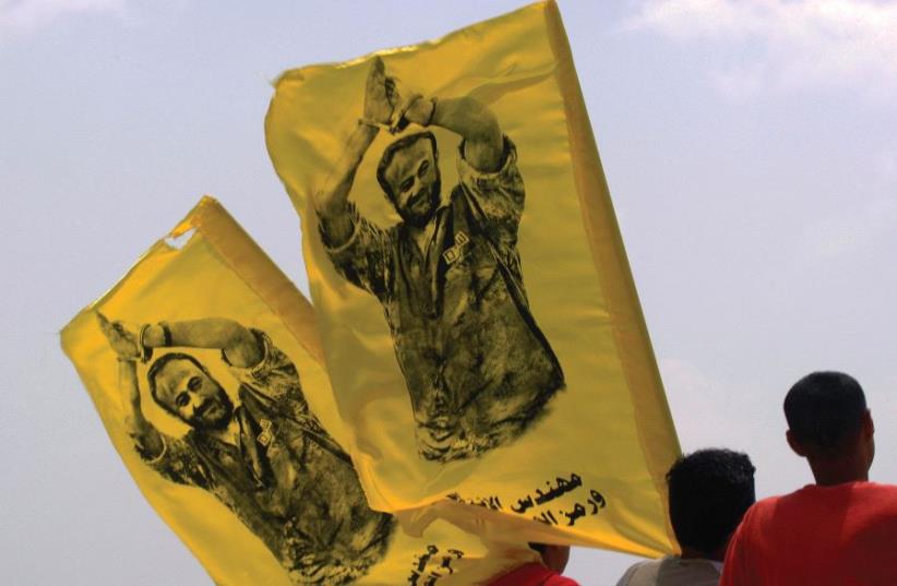 PALESTINIAN YOUTHS carry flags with the image of Marwan Barghouti during a protest in the West Bank (photo credit: REUTERS)