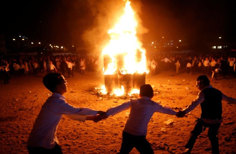 Ultra-Orthodox Jewish boys dance around a bonfire as they celebrate the Jewish holiday of Lag Ba'Omer in the city of Ashdod, Israel May 13, 2017 (photo credit: REUTERS)