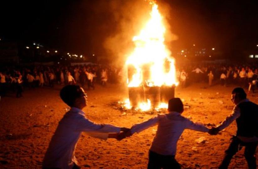 Ultra-Orthodox Jewish boys dance around a bonfire as they celebrate the Jewish holiday of Lag Ba'Omer in the city of Ashdod, Israel May 13, 2017 (photo credit: REUTERS)