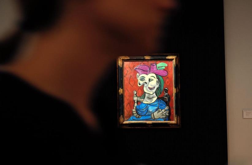 Visitors walk around Pablo Picasso's depiction of Dora Maar in "Femme assise, robe bleu", May 2017. (photo credit: JEWEL SAMAD / AFP)