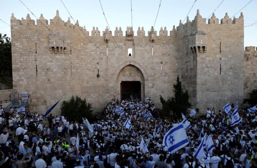 Israelis celebrate as they hold Israeli flags during a parade marking Jerusalem Day, the day in the Jewish calendar when Israel captured East Jerusalem and the Old City from Jordan during the 1967 Middle East War, just outside Damascus Gate outside Jerusalem's Old City May 24, 2017. (photo credit: RONEN ZVULUN/REUTERS)