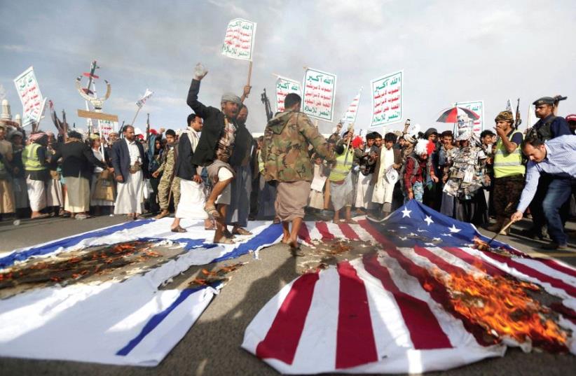 HOUTHI FOLLOWERS burn US and Israeli flags during a demonstration in Sanaa, Yemen in 2017 (photo credit: REUTERS)